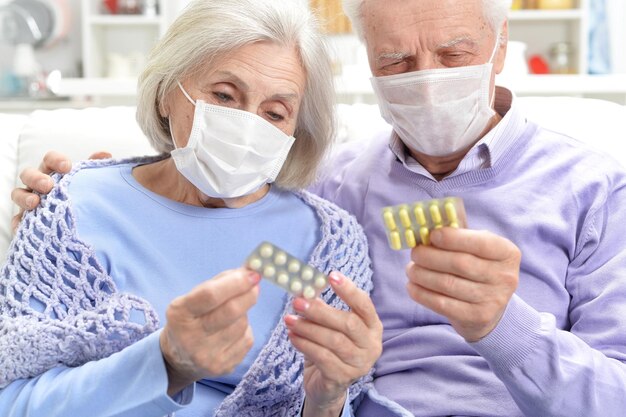 Retrato de anciana enferma y hombre con máscaras faciales con pastillas