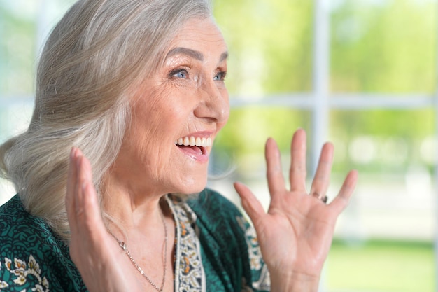 Retrato de una anciana feliz con camisa verde posando en casa