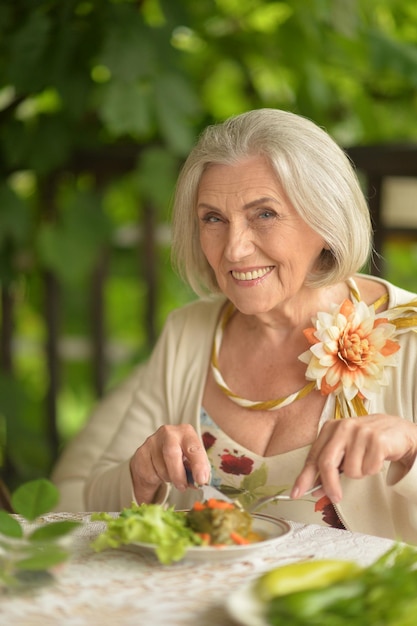 Retrato de una anciana feliz comiendo una deliciosa ensalada