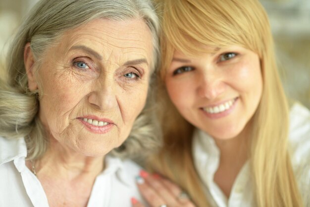 Retrato de una anciana feliz con una hija posando en casa