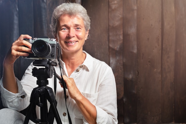 Retrato de anciana fotógrafa con cámara sobre fondo de madera