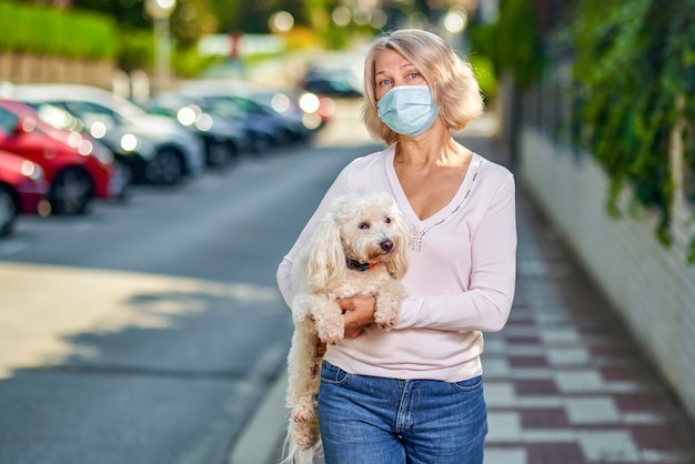 Retrato anciana con un perro al aire libre una máscara antivirus