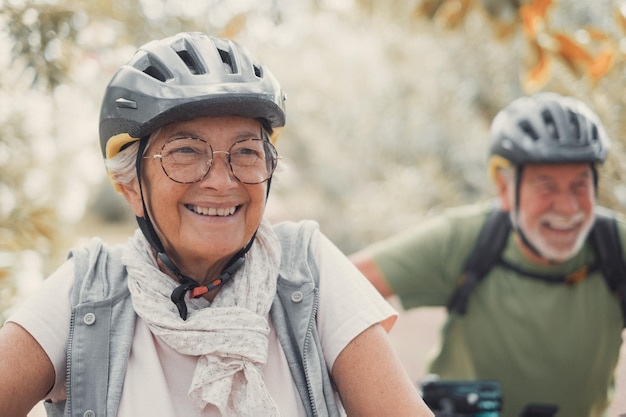 Retrato de una anciana sonriendo y disfrutando de la naturaleza al aire libre montando en bicicleta con su esposo riéndose Captura de cabeza de una mujer madura con anteojos sintiéndose saludable