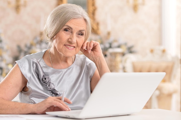 Retrato de una anciana sonriente usando una laptop