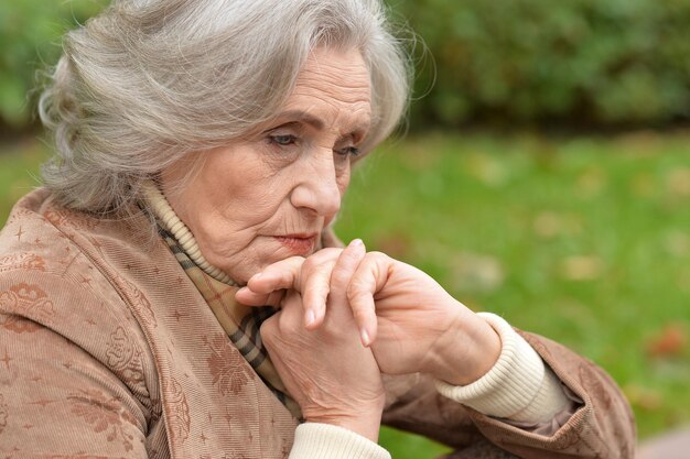 Retrato de una anciana triste en el parque otoño