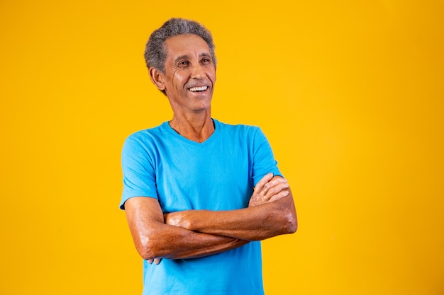 Retrato de anciano afro con los brazos cruzados sonriendo a la cámara.