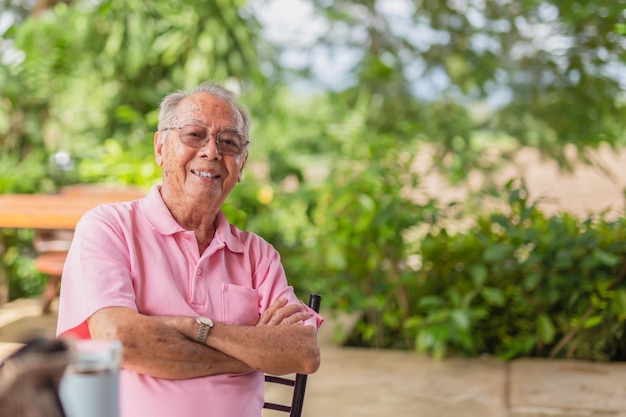 Foto retrato de un anciano asiático de 83 años con una sonrisa dentada sentado al aire libre en el jardín