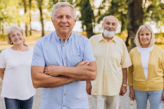 Foto retrato de un anciano de cabello gris contra el fondo de un grupo de ancianos en un parque de verano