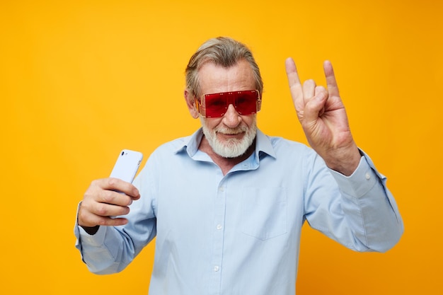 Retrato anciano camisas azules con gafas toma un selfie inalterado