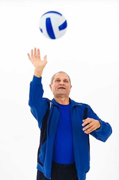 Retrato de un anciano en un chándal azul jugando con una pelota en blanco