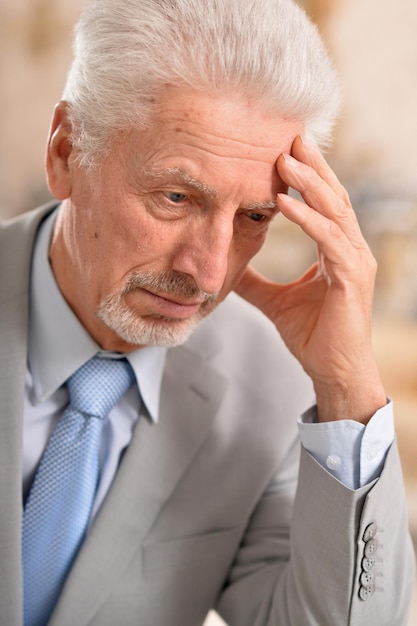 Retrato de un anciano con dolor de cabeza tomados de la mano en la frente en casa