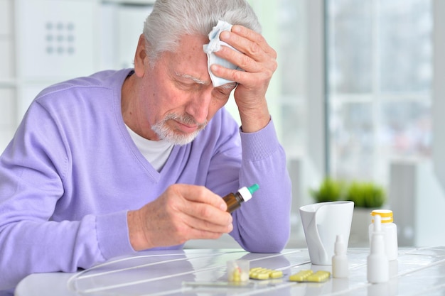 Retrato de un anciano enfermo tomando medicamentos