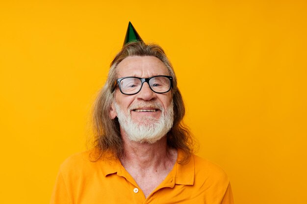 Retrato de un anciano feliz con una camiseta amarilla con una gorra en la cabeza con un divertido fondo amarillo