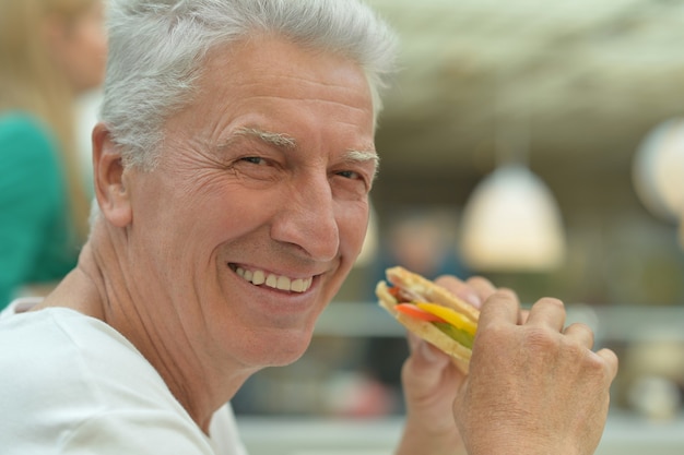 Retrato de un anciano feliz con comida rápida