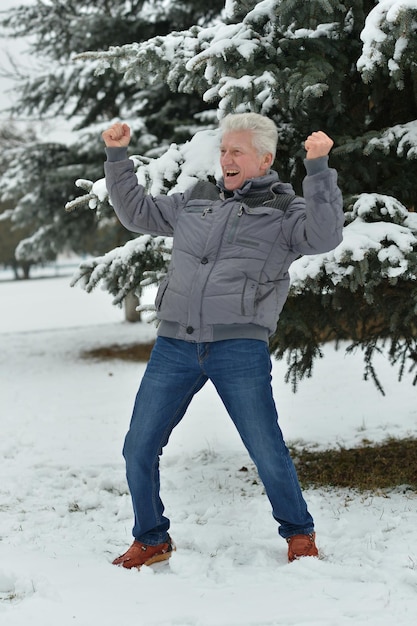 Retrato de un anciano feliz parado al aire libre en invierno