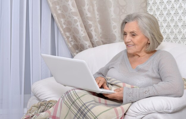 Retrato de un anciano feliz con portátil en casa