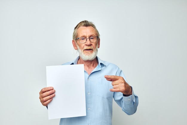 Retrato de un anciano feliz sosteniendo una hoja de papel copyspace posando antecedentes aislados