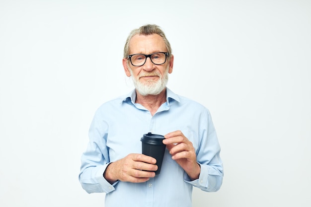 Retrato de un anciano feliz con un vaso negro en sus manos una bebida de fondo aislado