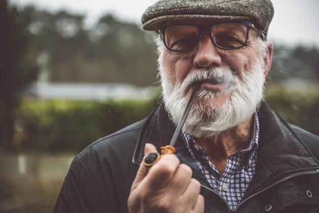 Foto retrato de un anciano fumando en el parque