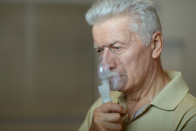 Retrato de anciano con inhalación de gripe