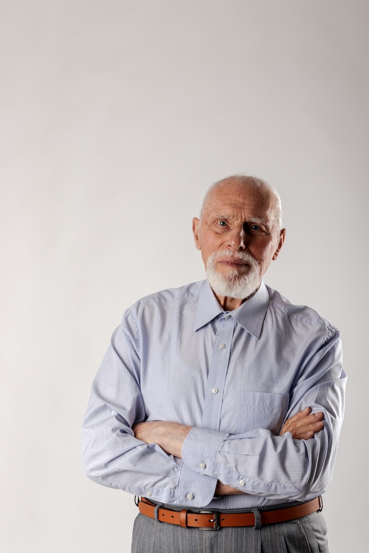 Foto retrato de un anciano de pie contra un fondo gris