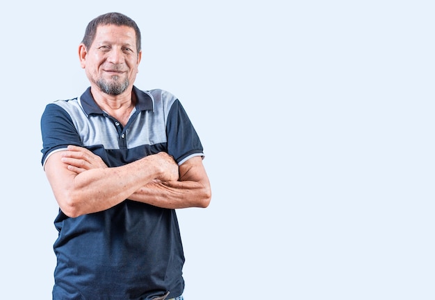 Retrato de un anciano sonriente con los brazos cruzados aislado Un anciano latino sonriante con los brazos cruzados casual en un fondo aislado