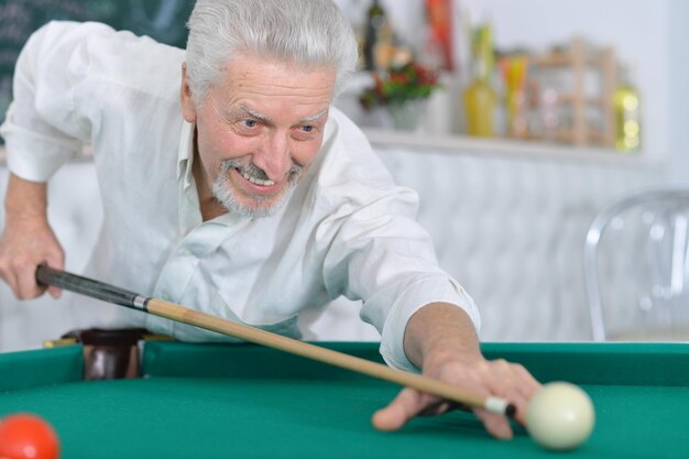 Retrato de un anciano sonriente jugando al billar