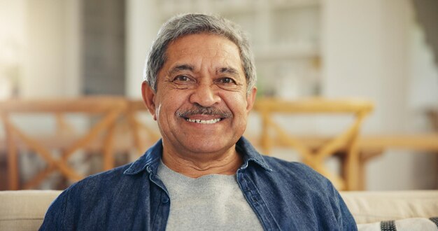 Retrato de anciano y sonrisa en casa para relajarse para la jubilación confianza y buen humor rostro feliz anciano y jubilado en el sofá en la sala de estar con sabiduría vejez y optimismo en Colombia