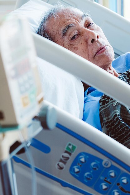 Retrato de un anciano tendido en una cama en un hospital