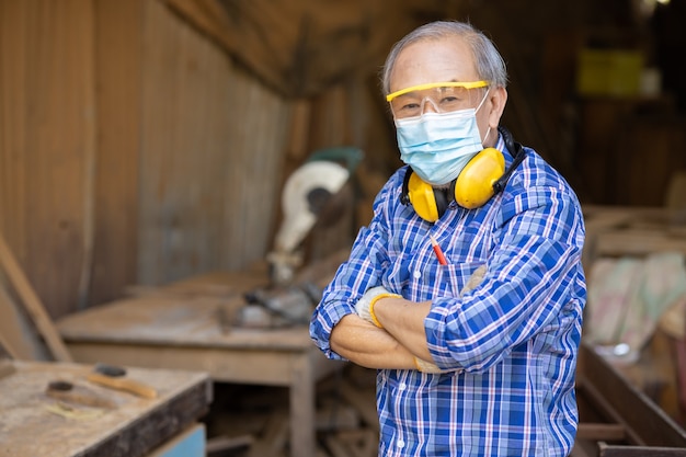 Foto retrato de un anciano trabajador de la madera hobby para una buena jubilación, maestro profesional maduro masculino asiático de muebles artesanales de madera hombre fabricante de madera.