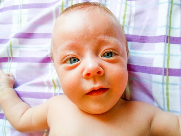 Foto retrato de ángulo alto de un bebé lindo tendido en la cama