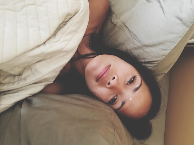 Retrato de ángulo alto de una mujer joven acostada en la cama en casa