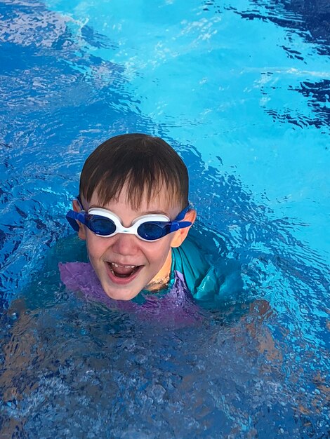 Foto retrato en ángulo alto de un niño feliz nadando en la piscina