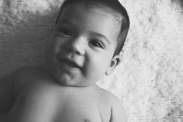 Foto retrato de ángulo alto de un niño lindo sonriente tendido en la cama en casa