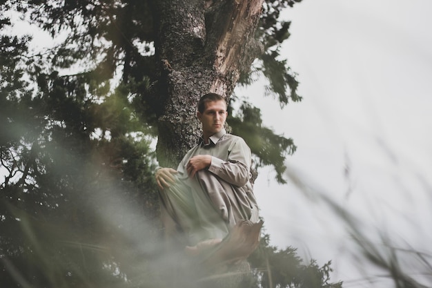 Retrato de bajo ángulo de un hombre sentado en un árbol