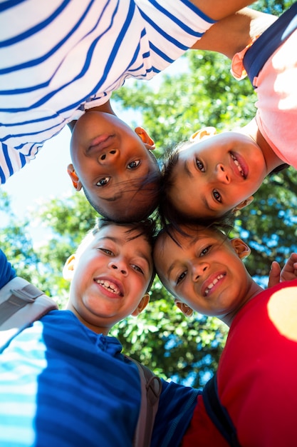 Retrato de ángulo bajo de niños felices formando huddle