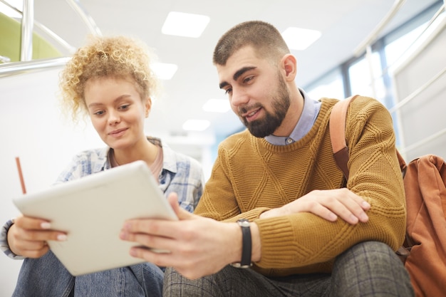 Retrato de ángulo bajo de pareja de estudiantes con tableta digital juntos