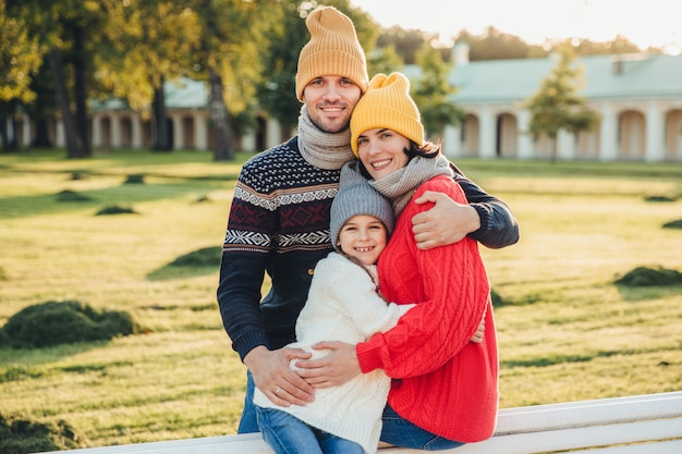 Retrato ao ar livre da bela mulher sorridente, homem bonito e sua filha pequena