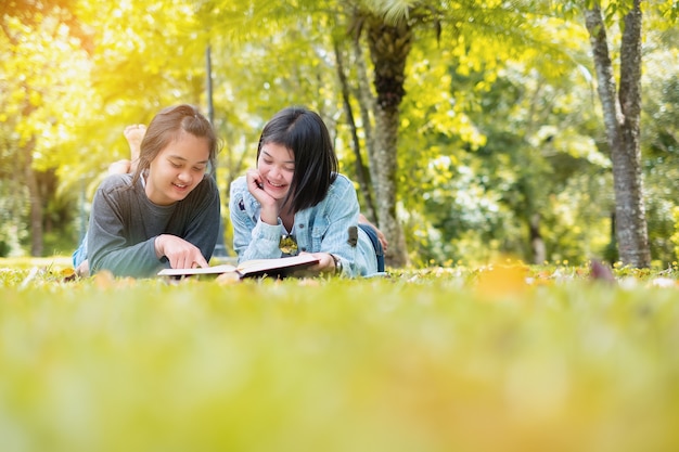 Retrato ao ar livre de duas meninas bonitos lendo um livro