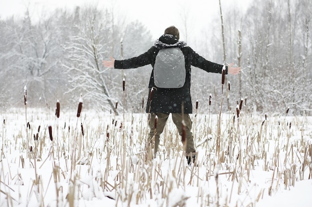 Retrato ao ar livre de homem bonito com casaco e casco. Homem barbudo na floresta de inverno.