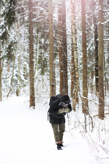 Retrato ao ar livre de homem bonito com casaco e casco. Homem barbudo na floresta de inverno.