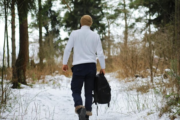 Retrato ao ar livre de homem bonito com casaco e casquinha. Homem barbudo na floresta de inverno.