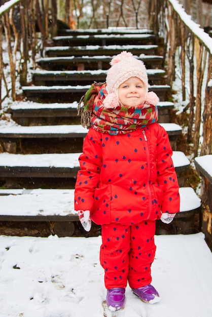 Retrato ao ar livre de inverno de uma adorável menina sonhadora com chapéu de malha e cachecol