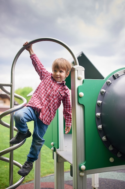 Foto retrato ao ar livre de menino bonito pré-escolar no parque infantil em verde natural