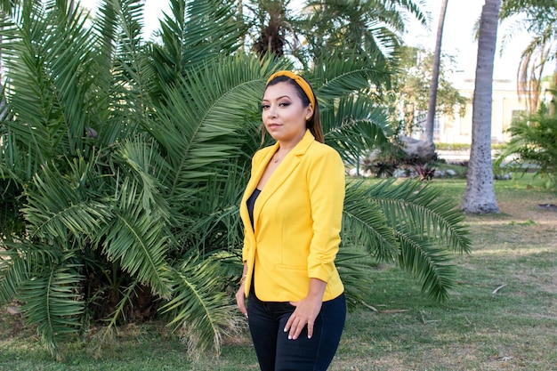 Retrato ao ar livre de mulher de casaco amarelo Retrato de jovem mexicana em um jardim ao pôr do sol