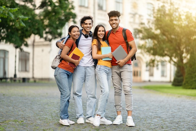 Retrato ao ar livre de um grupo feliz de estudantes multiétnicos perto do prédio da universidade