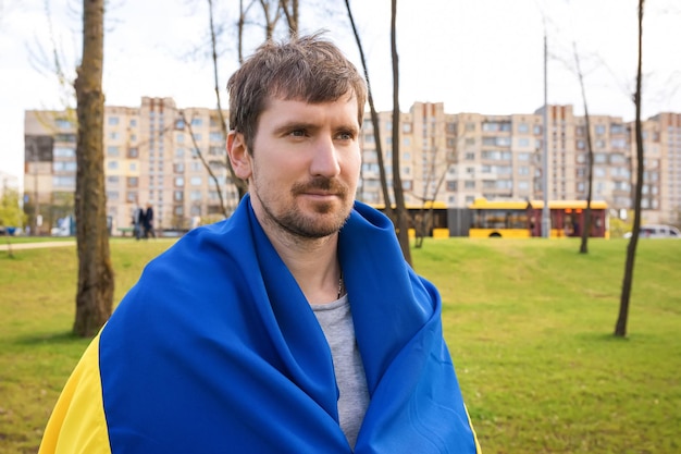 Retrato ao ar livre de um homem com a bandeira da ucrânia nas mãos ao ar livre no parque