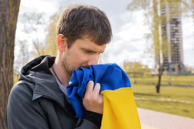 Retrato ao ar livre de um homem segurando a bandeira da Ucrânia na rua da cidade fechada