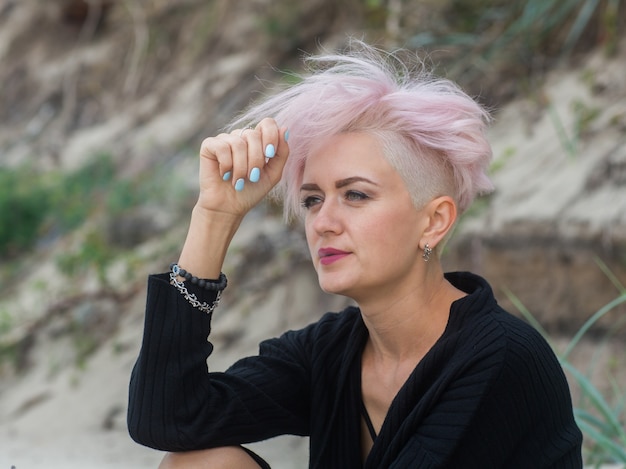 Foto retrato ao ar livre de uma bela jovem sexy com cabelo rosa e têmporas raspadas, fumando garota hippie