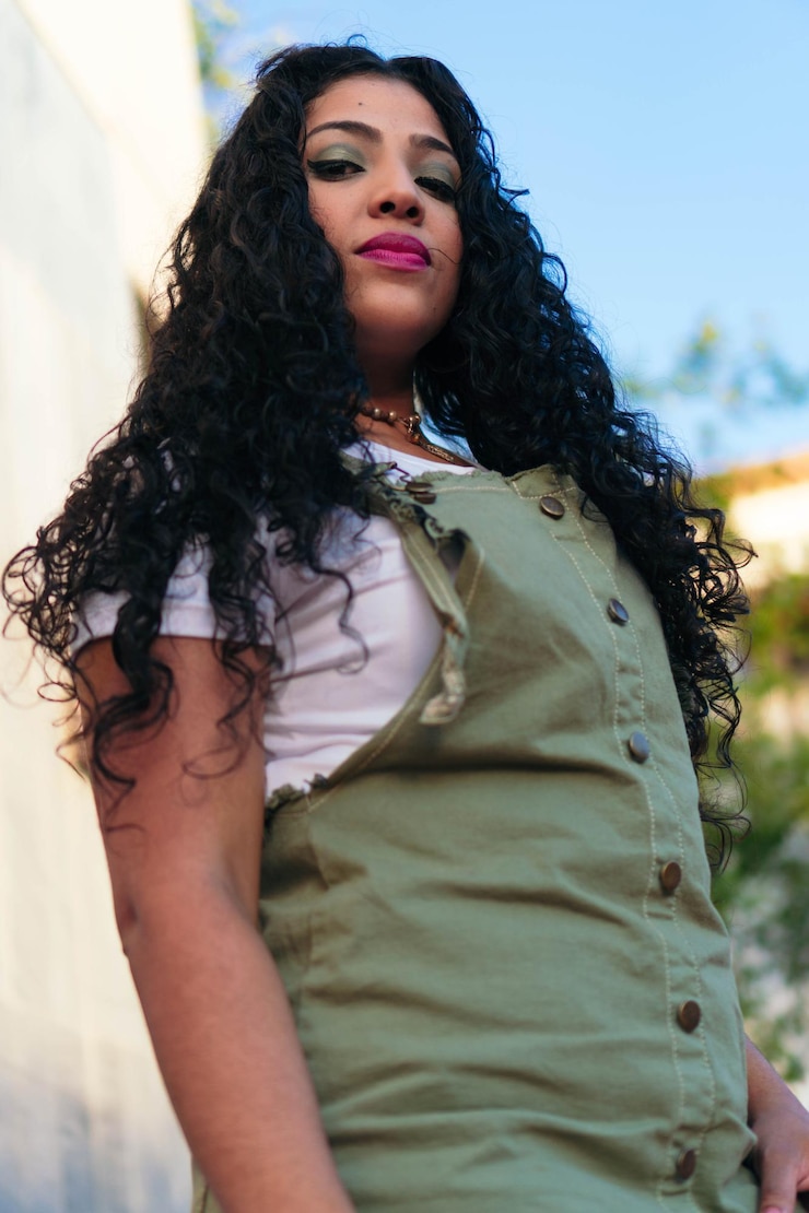 Foto retrato ao ar livre de uma jovem garota com cabelo encaracolado em pé na rua.
